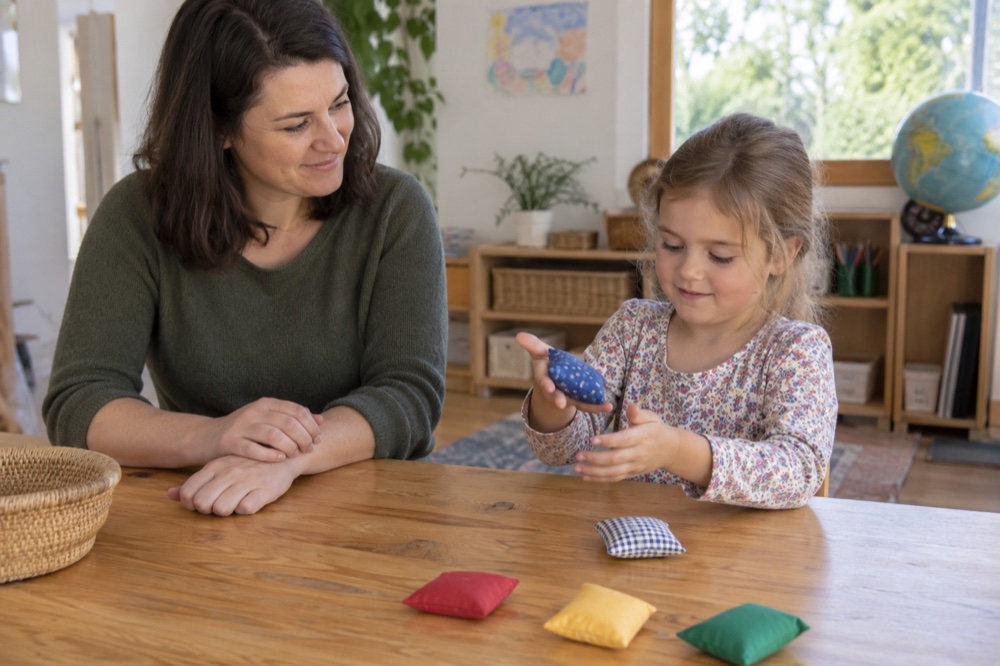 Una niña juega pasando un saquito de una mano a otra